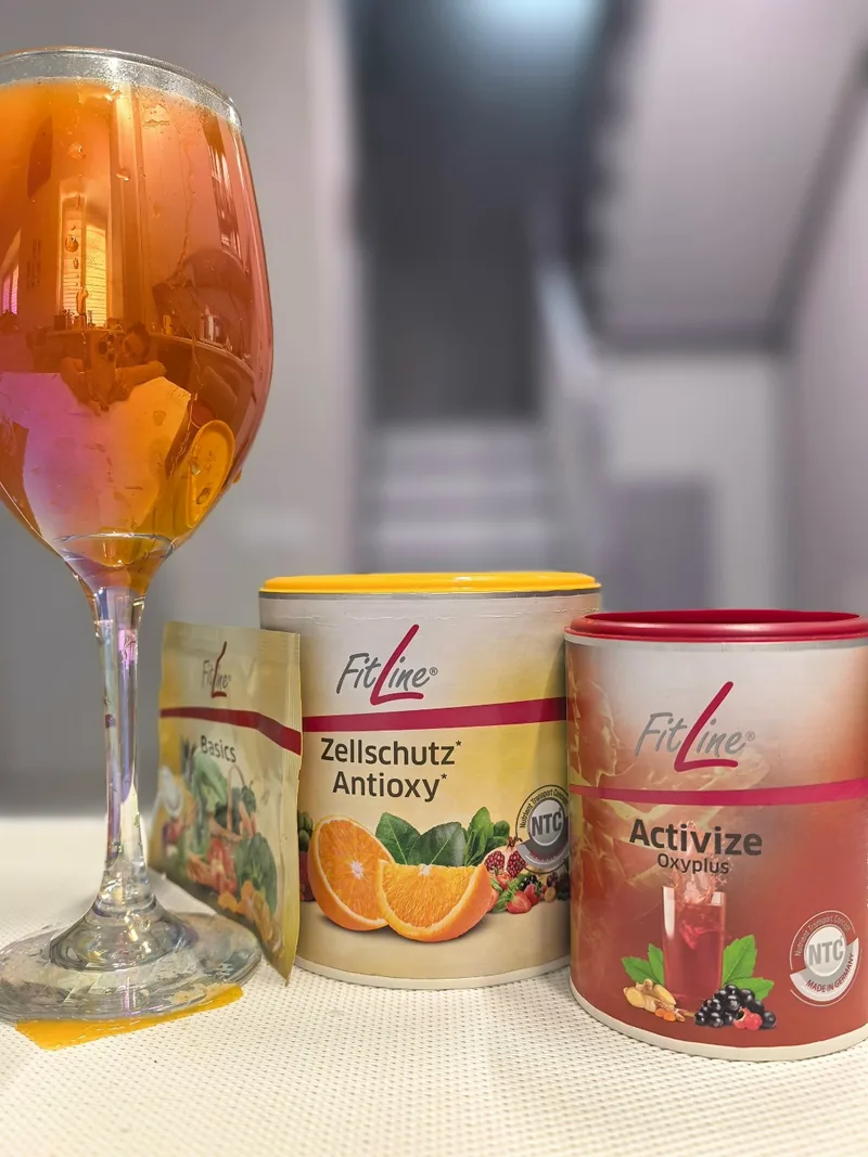 Напиток FitLine в бокале рядом с банками Zellschutz Antioxy и Activize Oxyplus